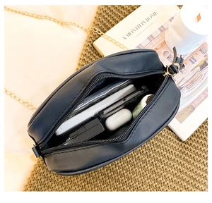 Internal view of black quilted camera bag showing storage for phone and accessories