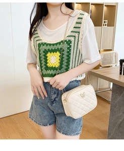 Close-up of white quilted crossbody bag with gold butterfly clasp and chain strap