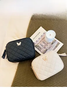 Detail of quilted crossbody handbags with metal butterfly decor and leather tassels