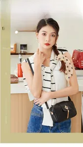 Sac bandoulière noir matelassé avec couronne dorée et pompon porté par un mannequin