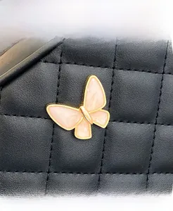 Close-up of a pink butterfly charm on a black quilted leather crossbody handbag