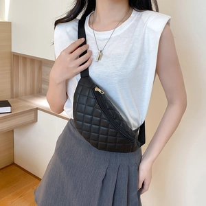 Women's black quilted waist bag with gold zipper shown on a model in a crossbody style
