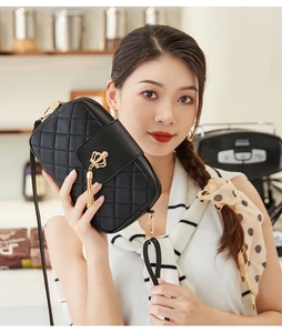 Détail d'un sac bandoulière noir matelassé avec fermoir couronne dorée et pompons