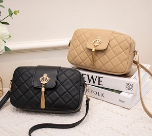 Détail de sacs bandoulière matelassés avec couronne en métal et pompons noir et beige