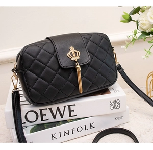 Détail du sac à bandoulière matelassé noir avec breloque couronne dorée et pompon