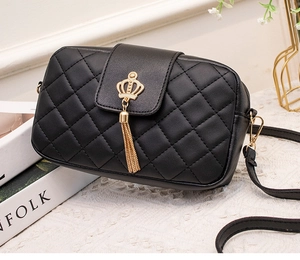 Détail du sac bandoulière matelassé noir avec boucle couronne dorée et pompons