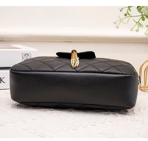 Détail du mini sac matelassé noir avec pompon doré et texture cuir élégante