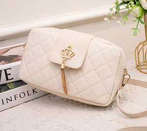 Détail du sac bandoulière matelassé blanc crème avec boucle couronne dorée et pompon
