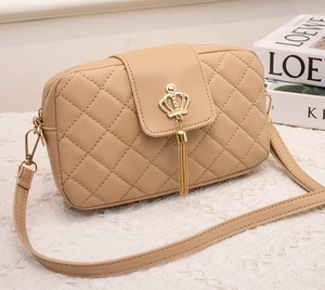 Détail du petit sac matelassé beige avec boucle couronne dorée et longs glands