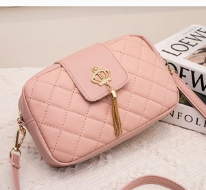 Détail du sac en cuir rose matelassé avec fermoir couronne dorée et pompon élégant