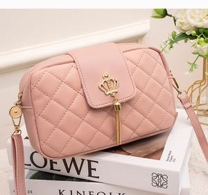 Détail du petit sac rose matelassé avec pompon couronne dorée sur fond décoratif