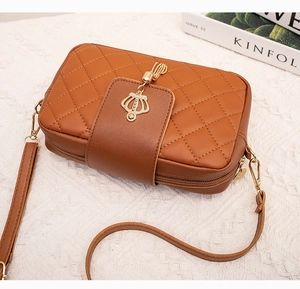 Détail du sac bandoulière marron matelassé avec breloque couronne dorée et zip