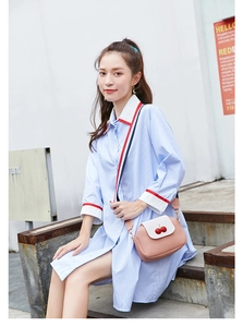 Detail of pink lychee texture crossbody bag with cherry decor and wide striped strap