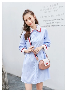 Detail of pink and white cherry crossbody bag worn over a blue striped shirt dress