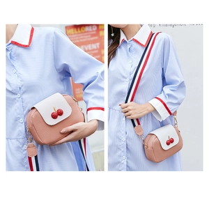 Detail of pink cherry crossbody bag featuring lychee texture and striped webbing strap