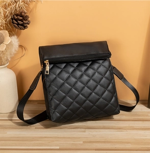 Détail du sac bandoulière matelassé noir avec zip doré et bandoulière tissée large