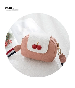 Detail of pink PU leather camera bag with sparkling cherry decor and striped strap
