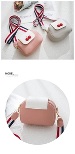 Detail of lychee textured leather crossbody bags with cherry decor and striped straps