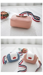 Detail of crossbody bag showing cherry decor, lychee texture, and striped strap