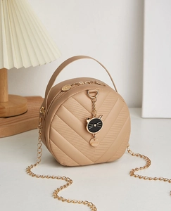 Detail of V-quilted texture and gold cat pendant on a khaki mini crossbody handbag