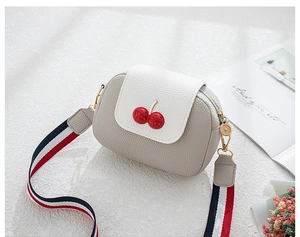 Detail of grey pebble leather crossbody bag with red cherry metal buckle and striped strap