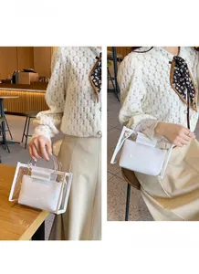 Detail view of transparent PVC crossbody bag with white inner pouch and round handles