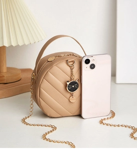 Detailed view of apricot crossbody bag with quilted chevron pattern and cat charm