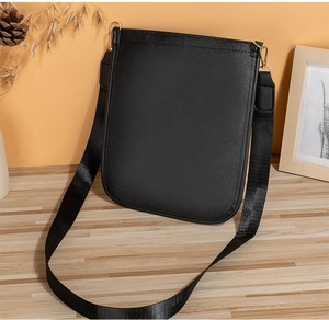Détail du sac bandoulière en cuir noir avec sangle large et attaches dorées