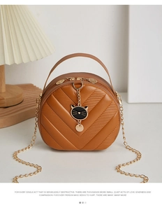 Close-up of caramel chevron quilted mini bag with golden chain and cat charm detail