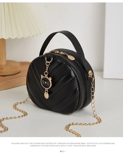 Detail of black round crossbody bag with V-quilted texture and cute cat charm pendant