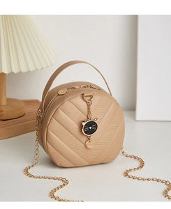 Detail of beige round crossbody bag with V-shaped quilting and gold cat pendant