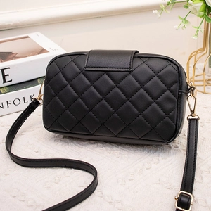 Sac bandoulière matelassé noir chic avec ferrures dorées et pompon sur fond de style de vie