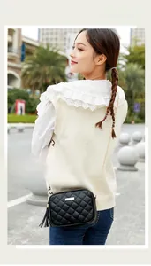 Detail of black quilted crossbody bag with gold chain strap and black tassel pendant