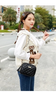 Close-up of black quilted shoulder bag with gold chain strap and leather tassel detail