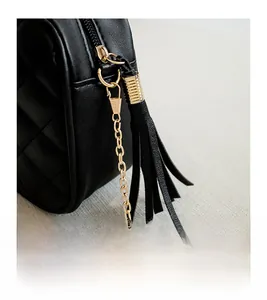 Macro view of black quilted leather side with pale gold zipper and tassel detail