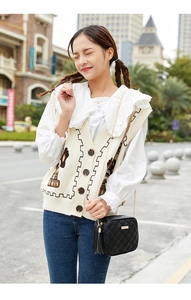 Detail of a black quilted crossbody bag with gold chain paired with a floral knit vest