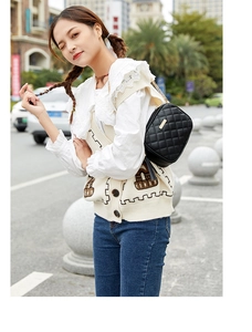 Detail of black quilted crossbody bag with gold hardware and chain strap on a model