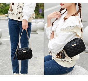 Detail of black quilted mini bag with gold chain strap and tassel charm in outdoor use