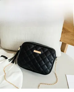 Detail of black quilted shoulder bag with gold chain and stylish tassel accent