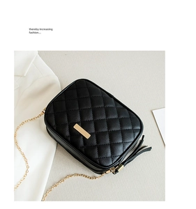 Detail of black quilted shoulder bag with gold hardware and elegant tassel charm