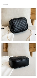 Detail of black quilted crossbody bag with gold chain strap on a chic beige cushion