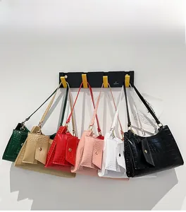 Detail view of multi-color crocodile texture shoulder bags hanging on a white wall