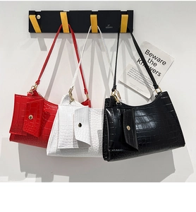 Detailed display of three crocodile-patterned baguette bags in red, white, and black colors