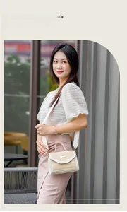 Chic straw and white leather crossbody bag with top handle worn by a model
