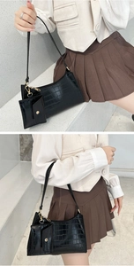 Detail of black crocodile texture shoulder bag with mini coin purse and gold hardware