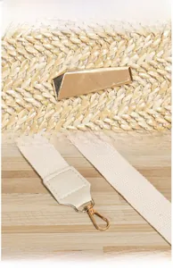 Detail of straw bag featuring polished gold metal buckle and reinforced fabric strap