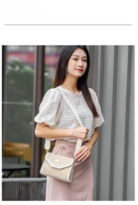 Beige woven straw crossbody bag with white leather trim and metal clasp on street model