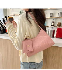 Detailed view of a pink crocodile pattern underarm bag with a matching small pouch