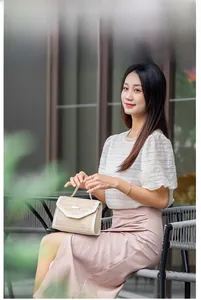 Detail of woven straw handbag with white leather flap and metallic buckle decoration