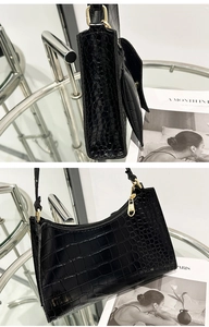 Detail of black crocodile pattern shoulder bag with gold hardware and mini pouch charm